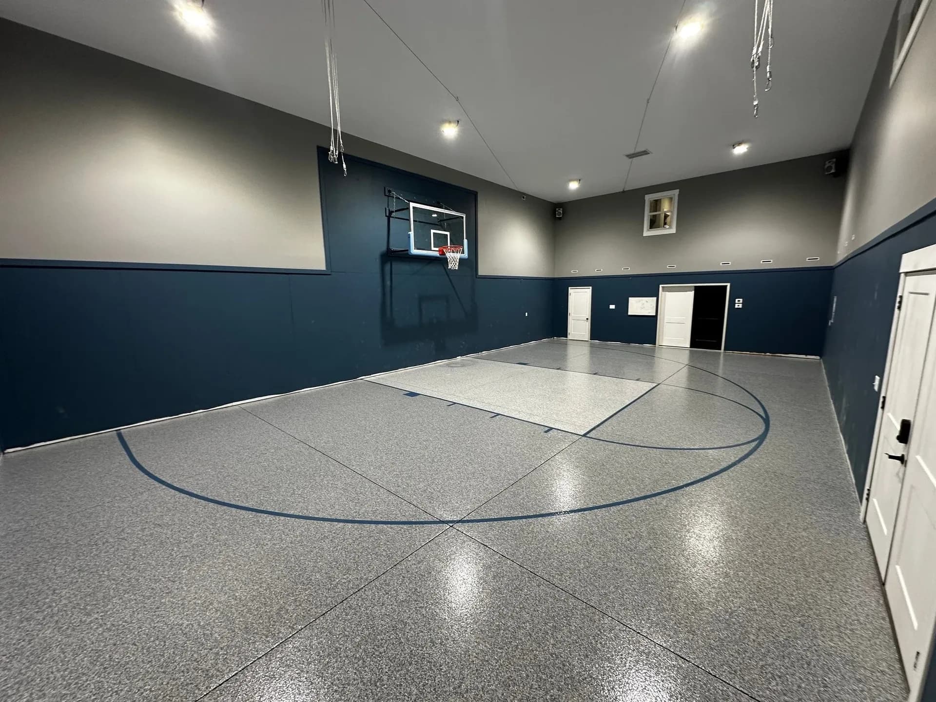 A blue and gray indoor half basketball court with new concrete coating flooring.