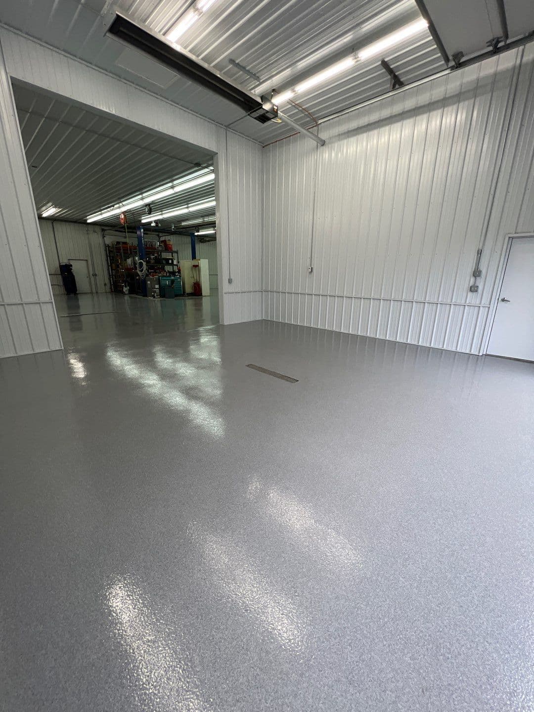 A commercial warehouse space with white metal walls and newly-coated gray quartz flooring.