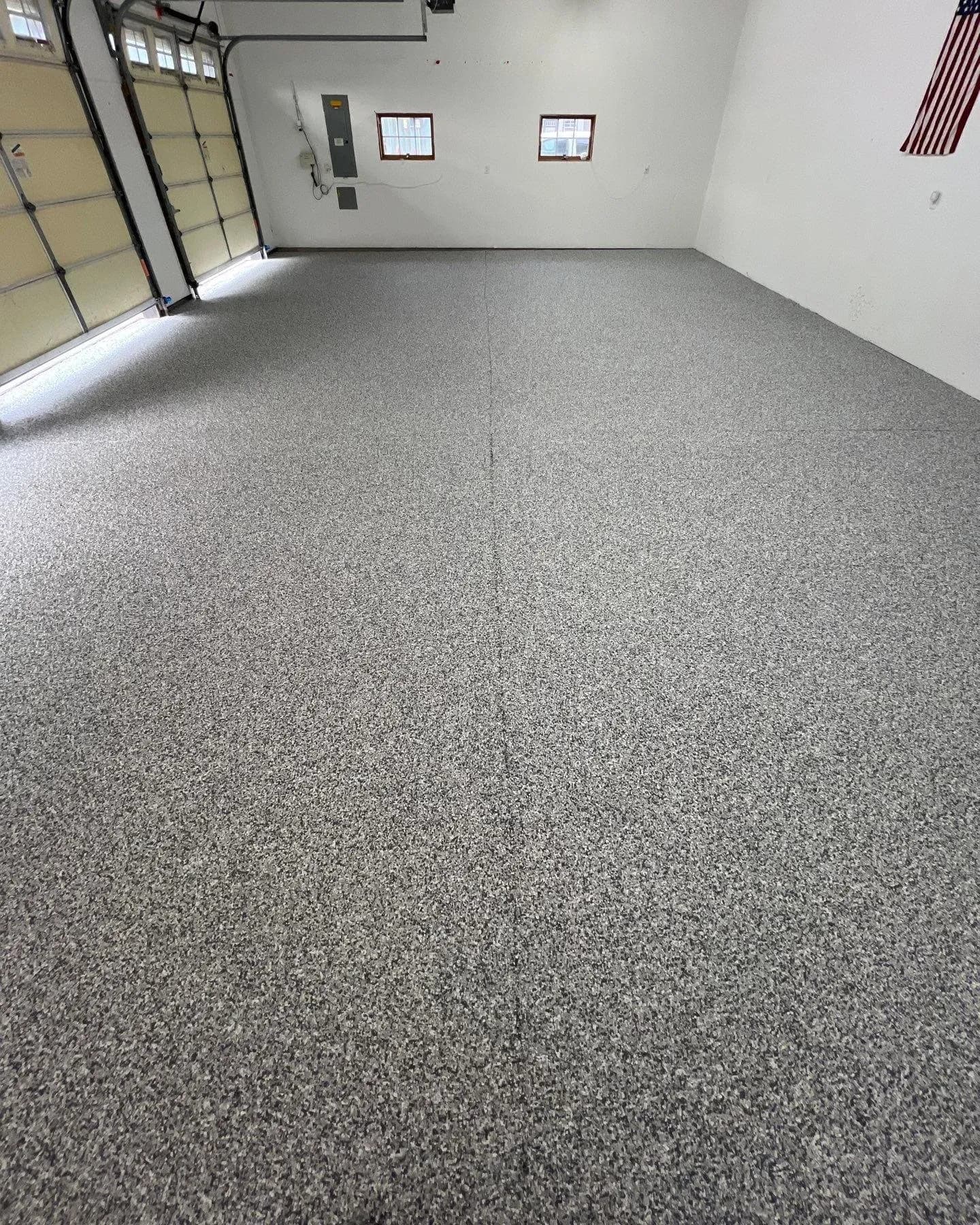 A commercial garage space with multiple bays and new black, white, and gray flecked concrete coated flooring.