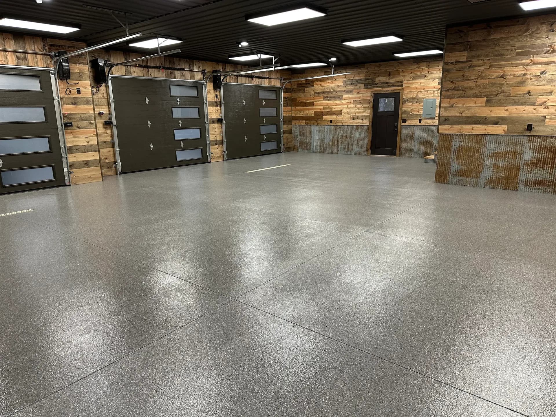 A commercial space with newly-coated dark grey flecked concrete flooring.