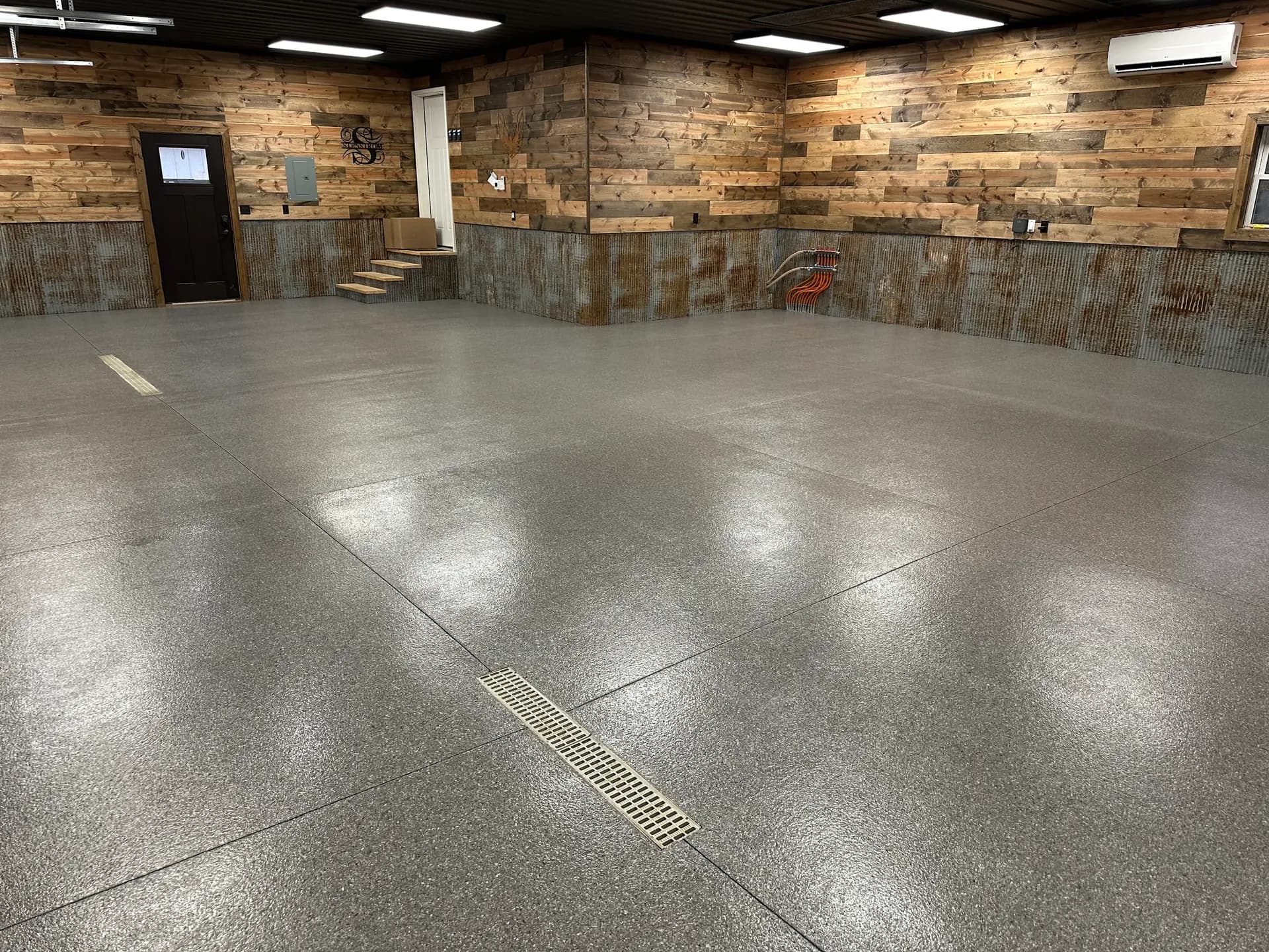 A commercial space with newly-coated dark grey flecked concrete flooring.
