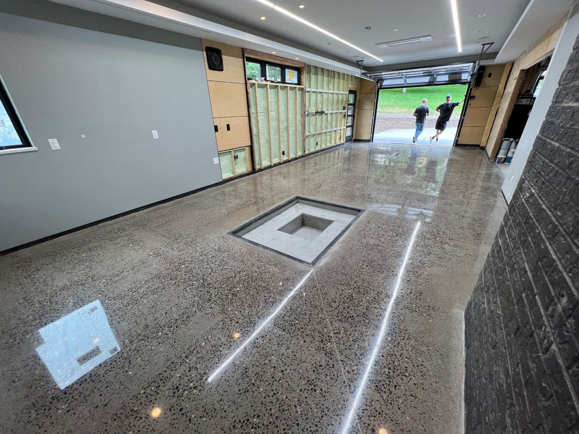 A commercial space with gray walls and polished concrete flooring with multi-colored stone accents.