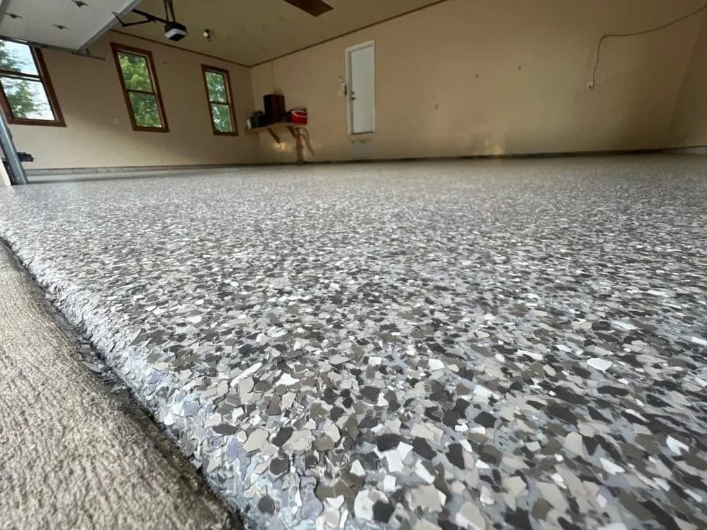 A close-up of a garage with new gray flecked concrete coated flooring.