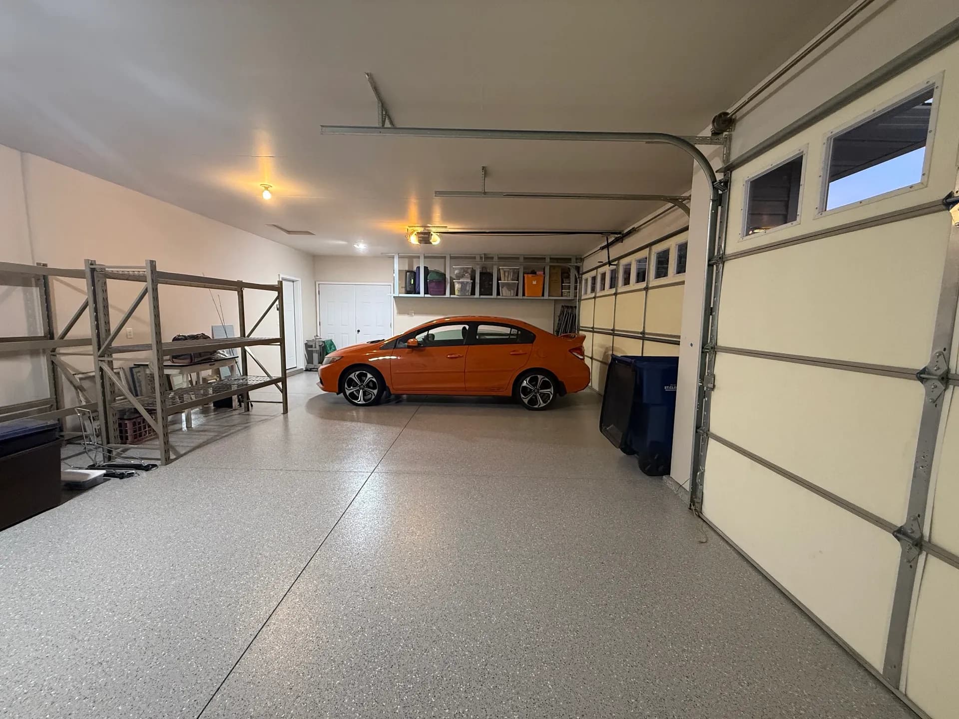 Custom color flecked concrete coated garage floor with an orange car in the background.