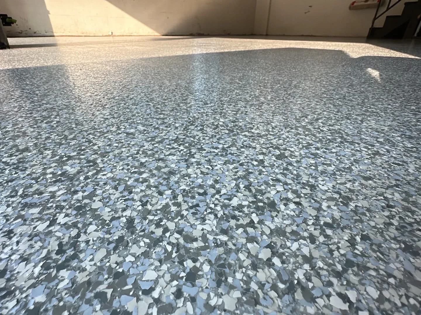 A close up of dark gray, light gray, and white flecked flake concrete flooring.