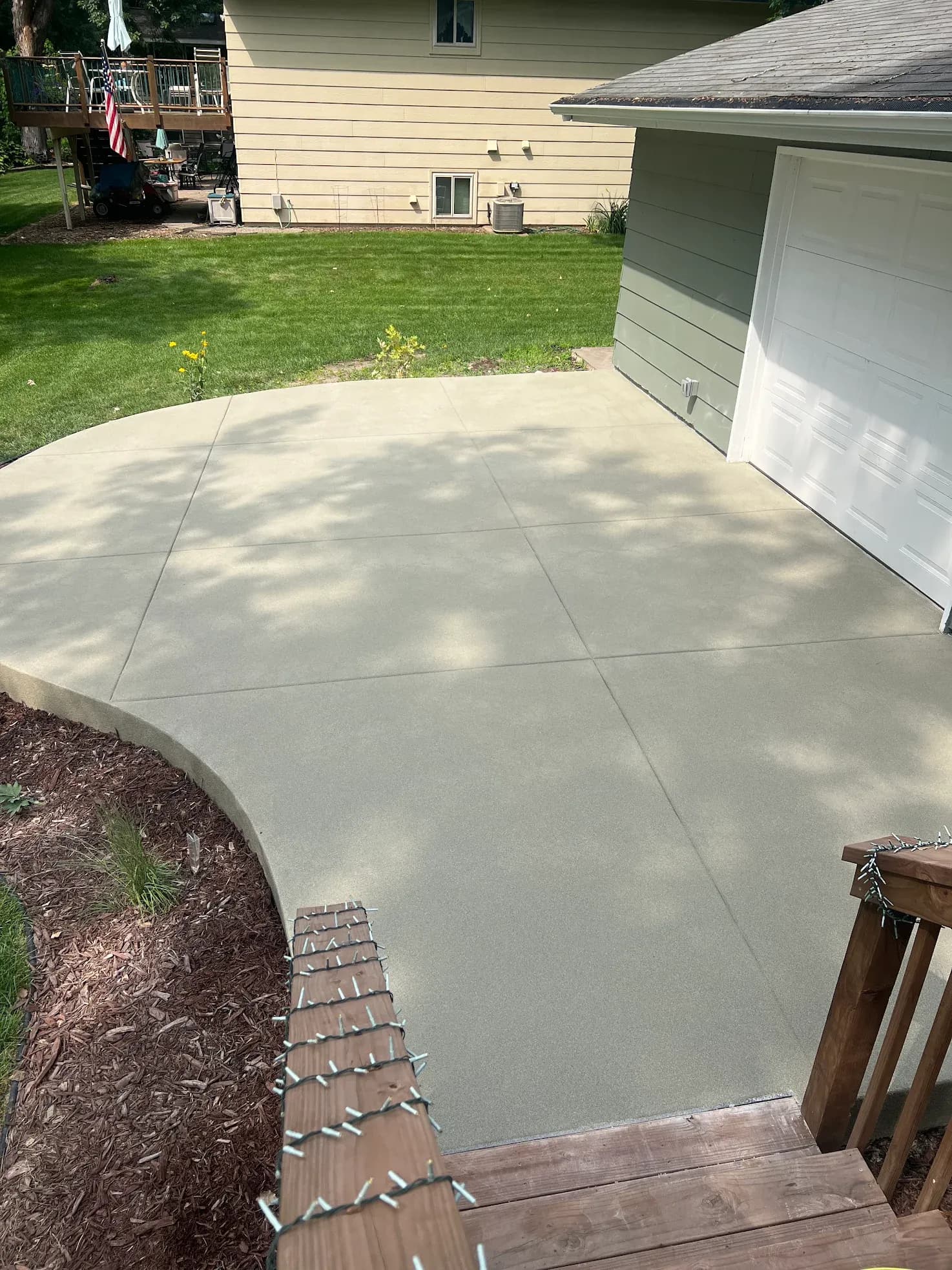 A concrete coated patio and driveway area in front of a garage.