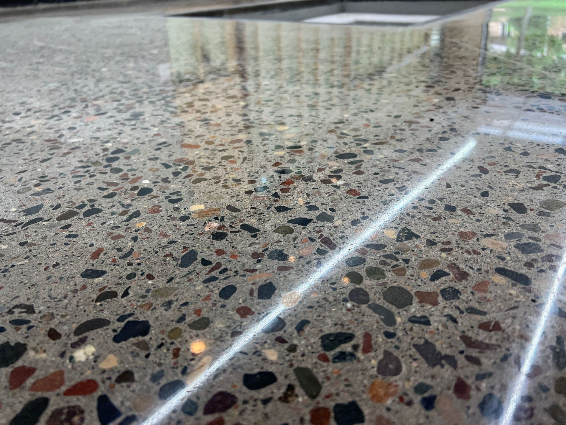 A close-up of polished concrete flooring with multi-colored stone accents.