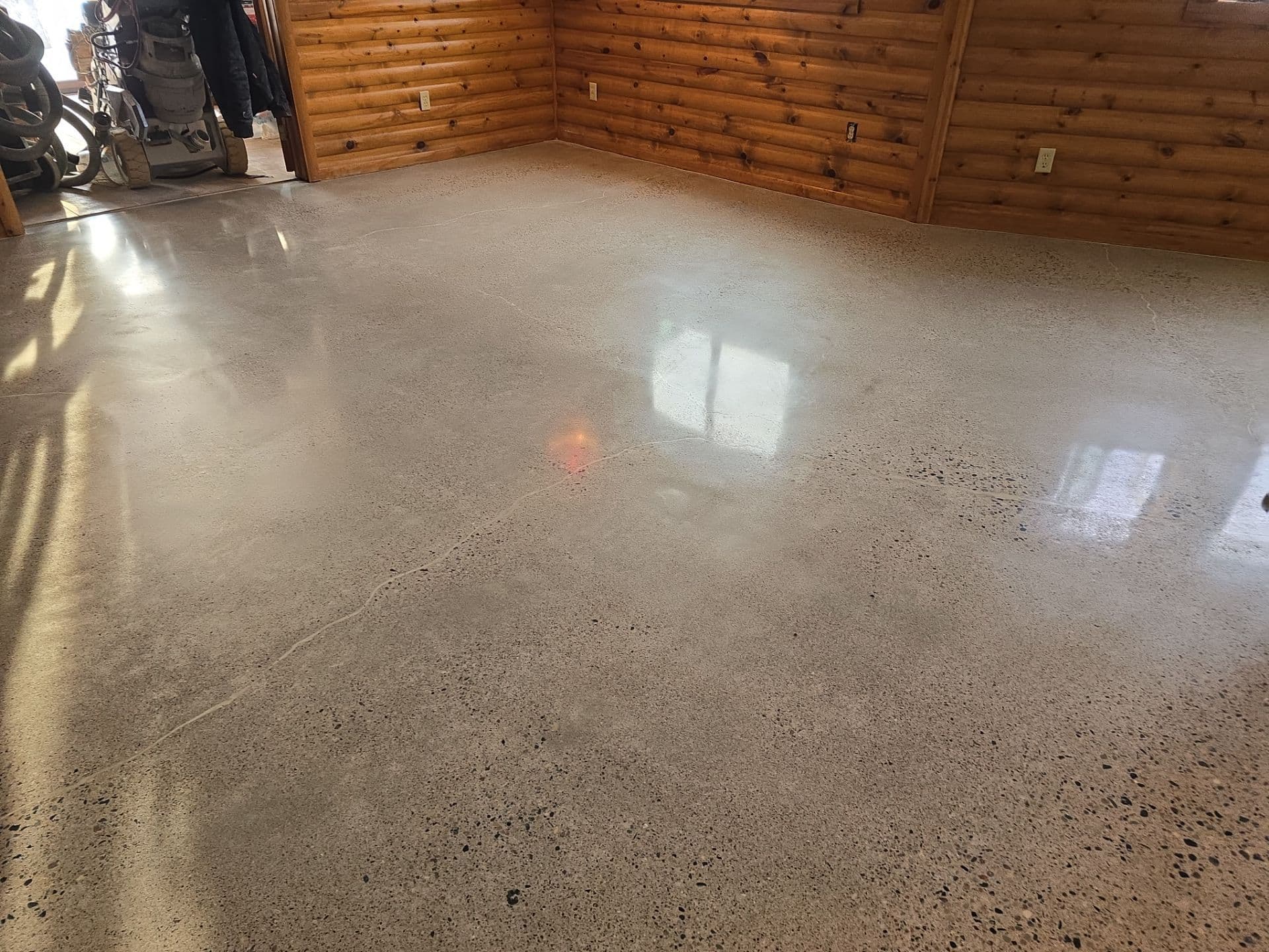 A tan-colored polished concrete floor in a room with wood panel siding.