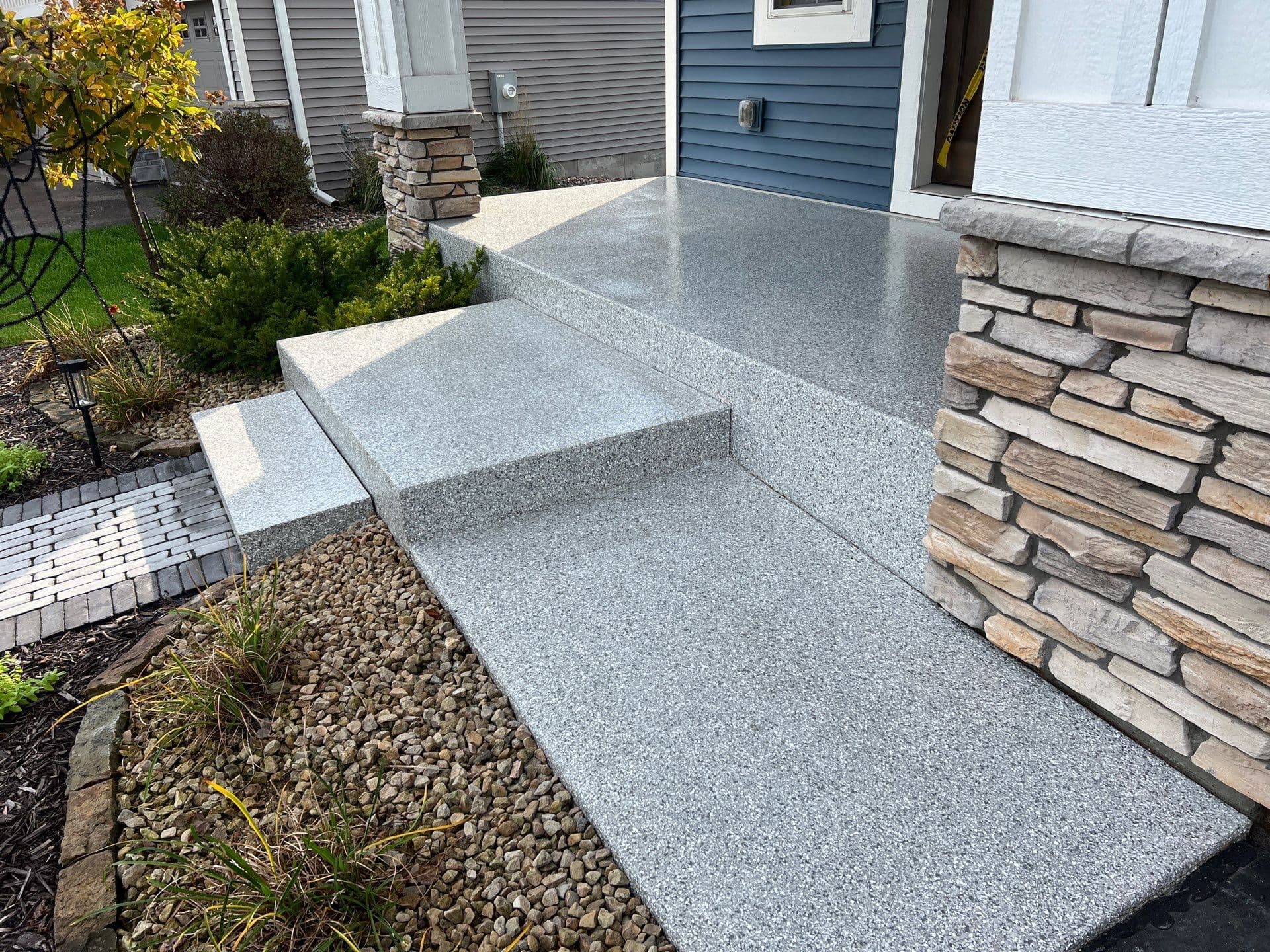 A front stoop and steps with a light gray flecked concrete coated surface.