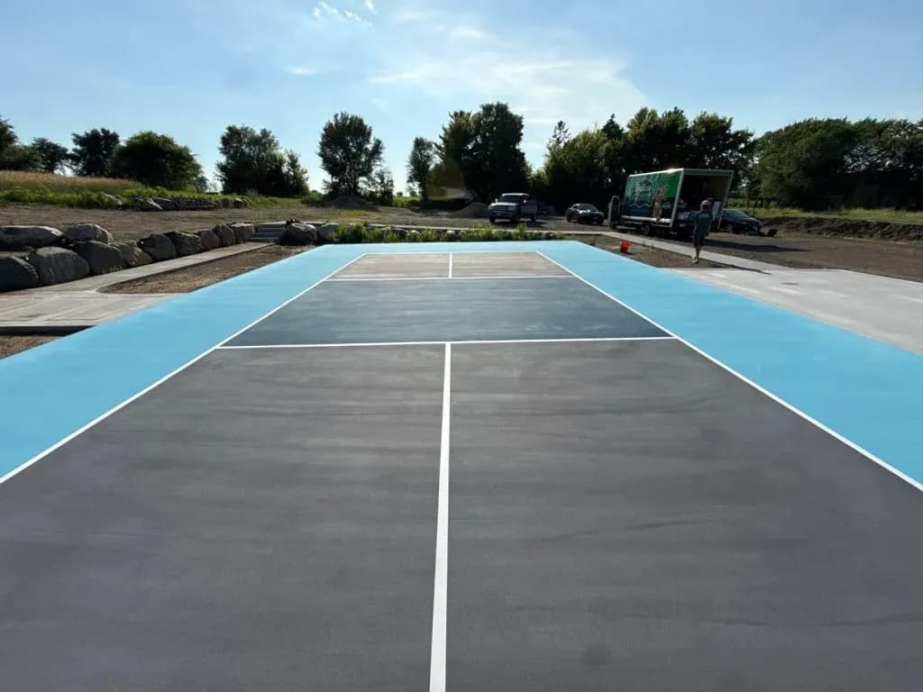 A newly-coated black, blue, and white pickleball concrete flooring court.