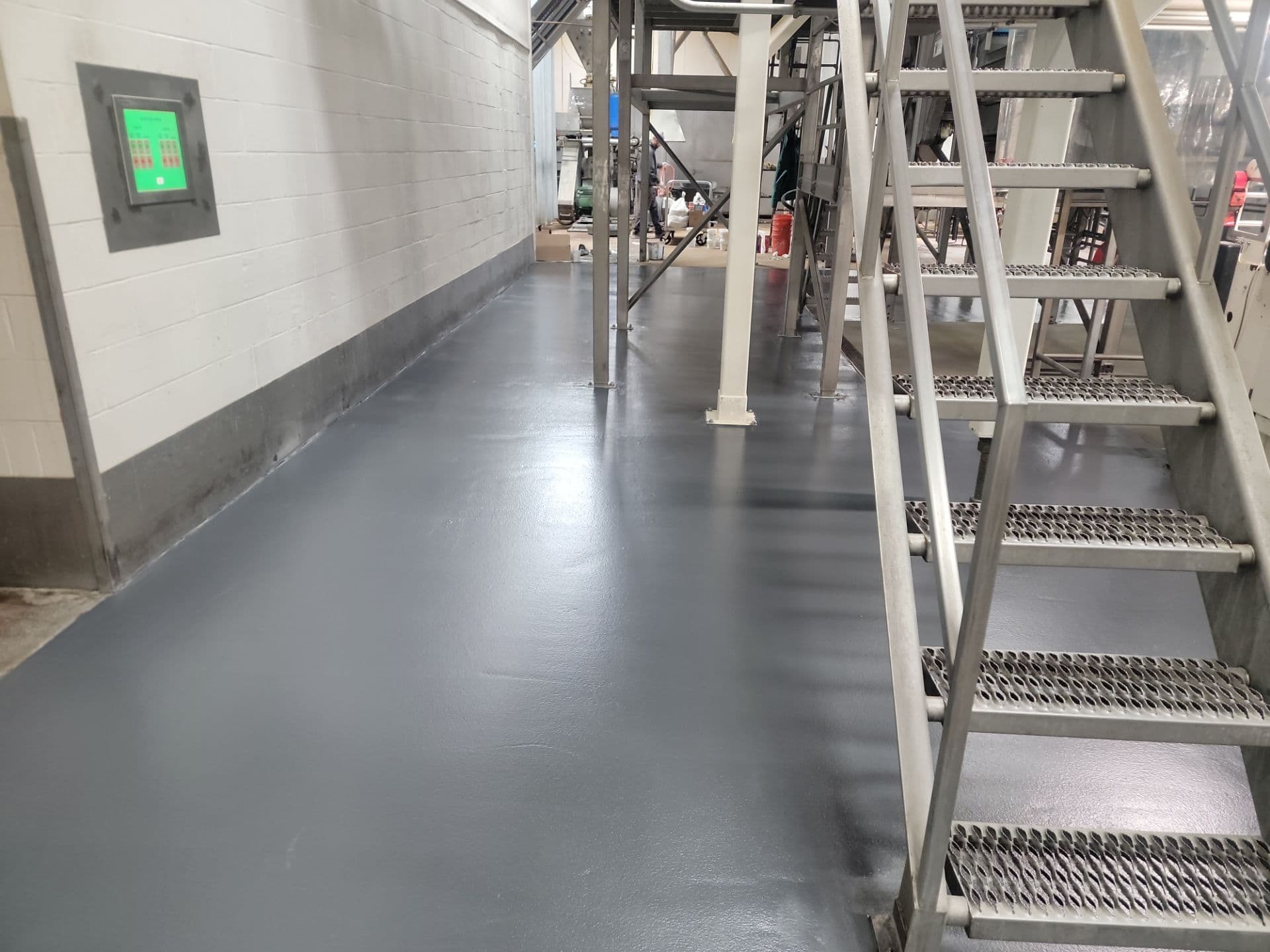 Solid gray urethane cement flooring in a commercial industrial space. Metal stairs are off to the right side.